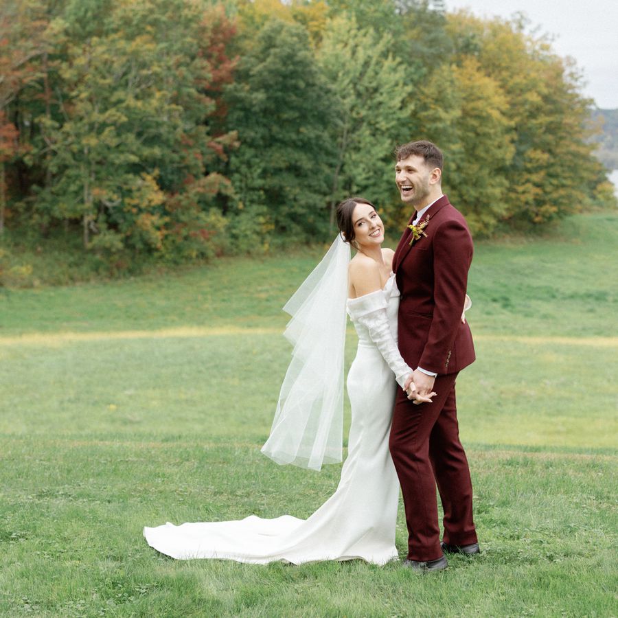 bride and groom posing in front of fall foliage