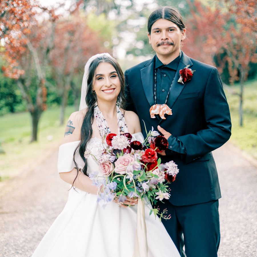 Native American bride and groom posing for portrait outdoors against fall foliage