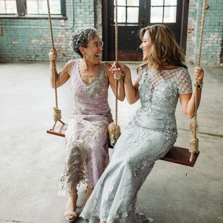 Mother of the groom and mother of the bride laughing and smiling on a swing
