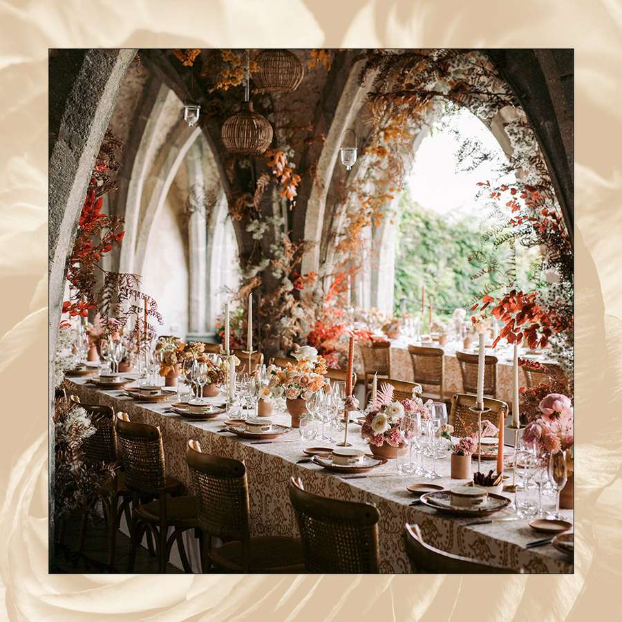 wedding tablescape with florals and lanterns along arches and taper candles on tablecloth
