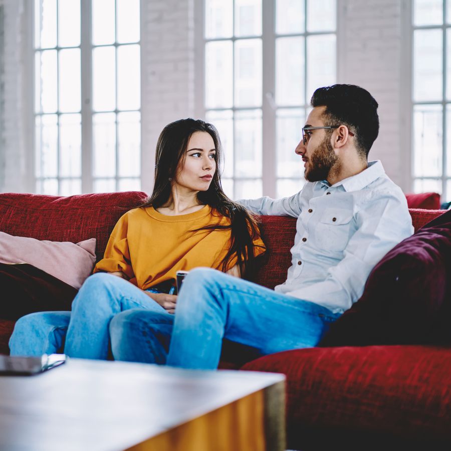 Boyfriend talking with girlfriend on a sofa in an apartment