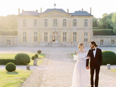 A bride and groom walk outside their wedding venue in France.