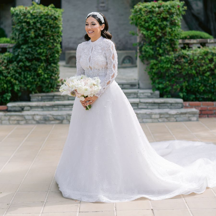 bride smiling holding her wedding bouquet while wearing a long sleeve ball gown 