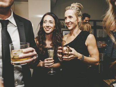 Women and men holding drinks and wearing cocktail party attire