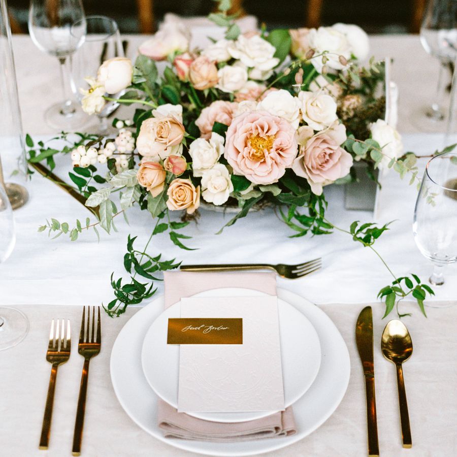 A wedding reception table with pink roses, greenery, and pink and white accents.