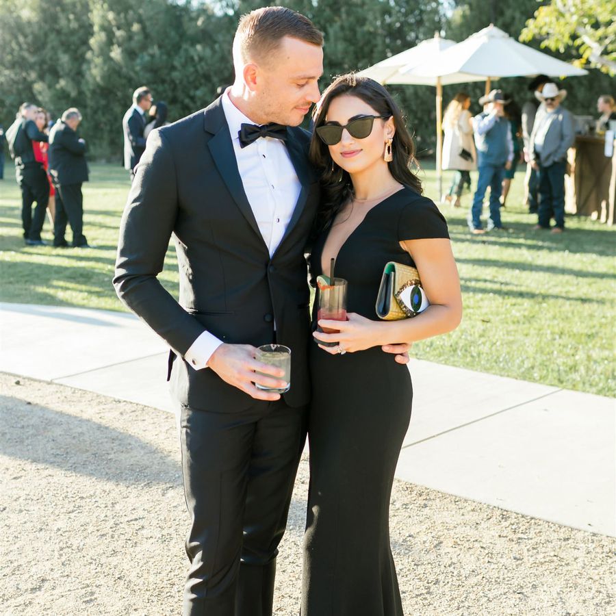 male and female wedding guest wearing black-tie attire and holding drinks