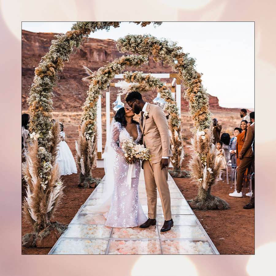 Bride and groom kissing under a floral arch