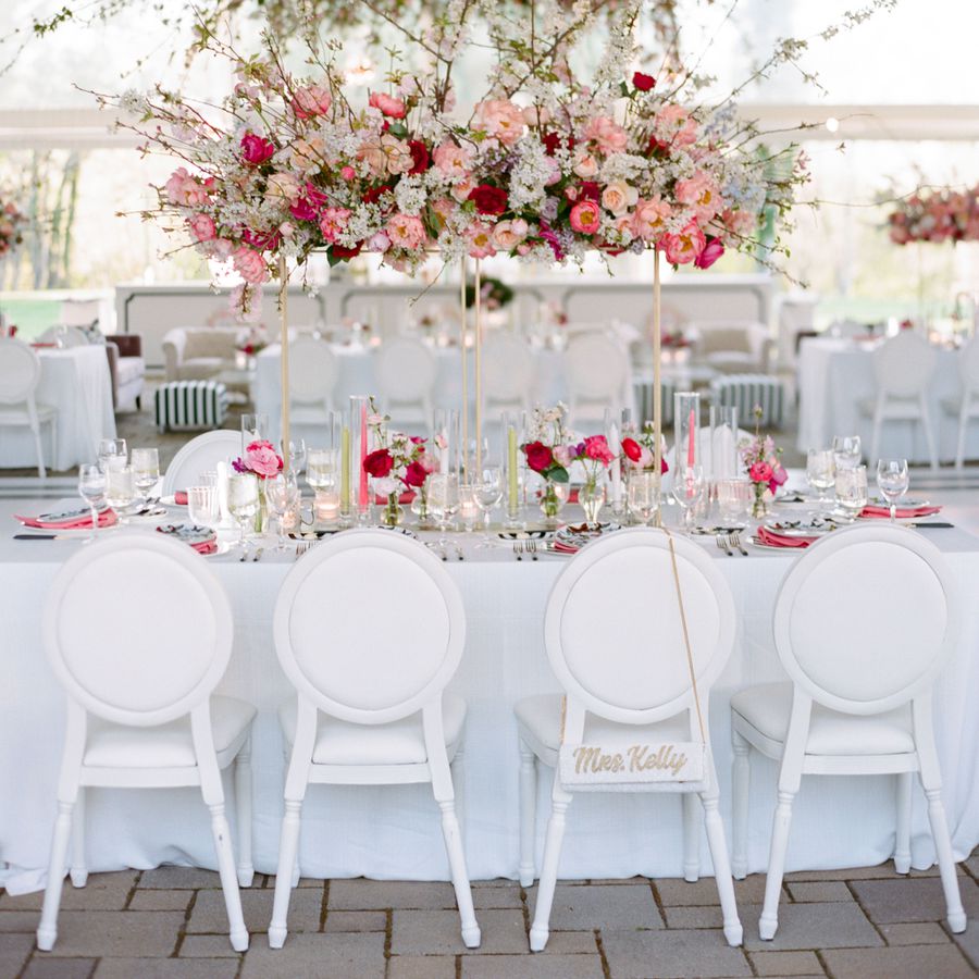 A spring wedding head table featuring a hanging floral installation and pink flowers.