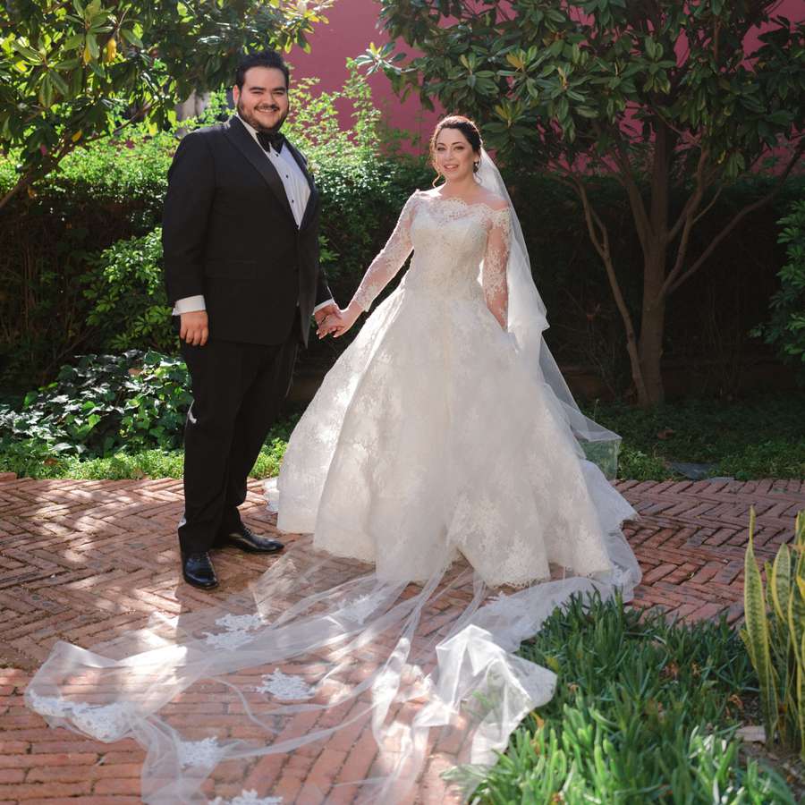 bride in lace Monique Lhuillier ballgown and groom pose for newlywed portrait