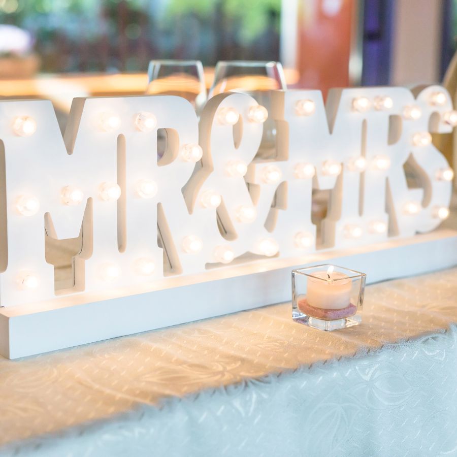 A white, lit-up Mr. and Mrs. sign at a wedding. 