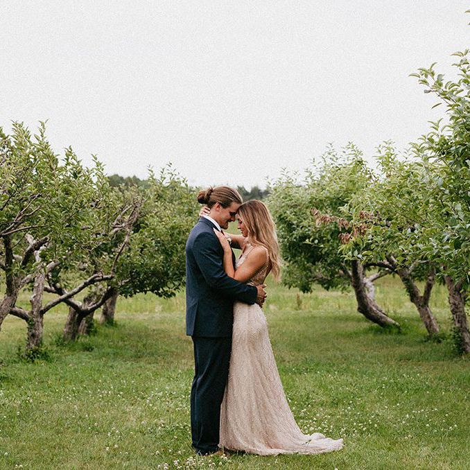 Bride and groom in an apple orchard field surrounded by apple trees at The Meadow Barn in South Dakota.