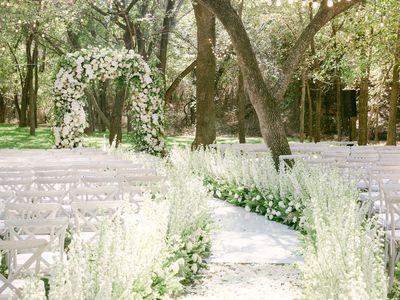 Outdoor Wedding Ceremony in Garden with Floral-Lined Aisle and Floral Arch