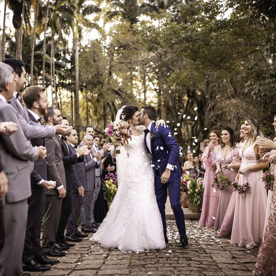 Bride and groom kissing one another while their wedding party throws flower petals
