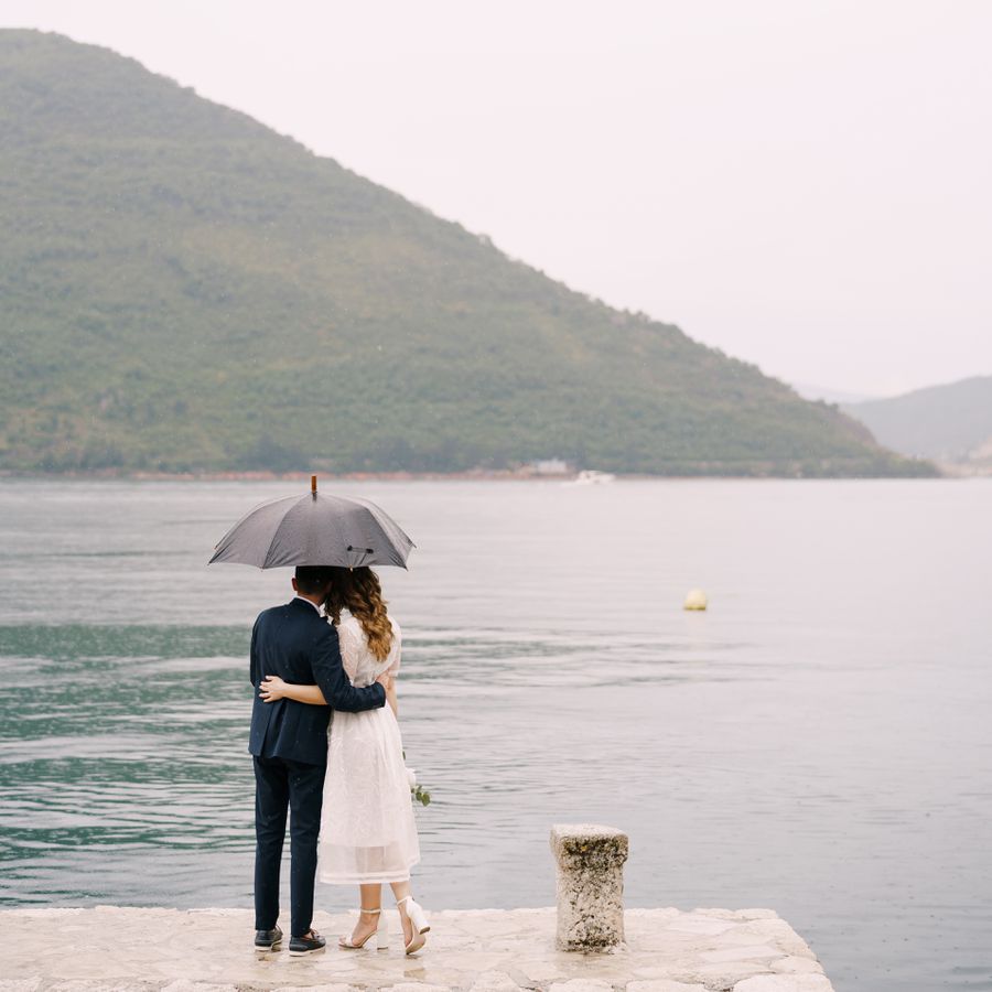 Couple under umbrella looking at a lake