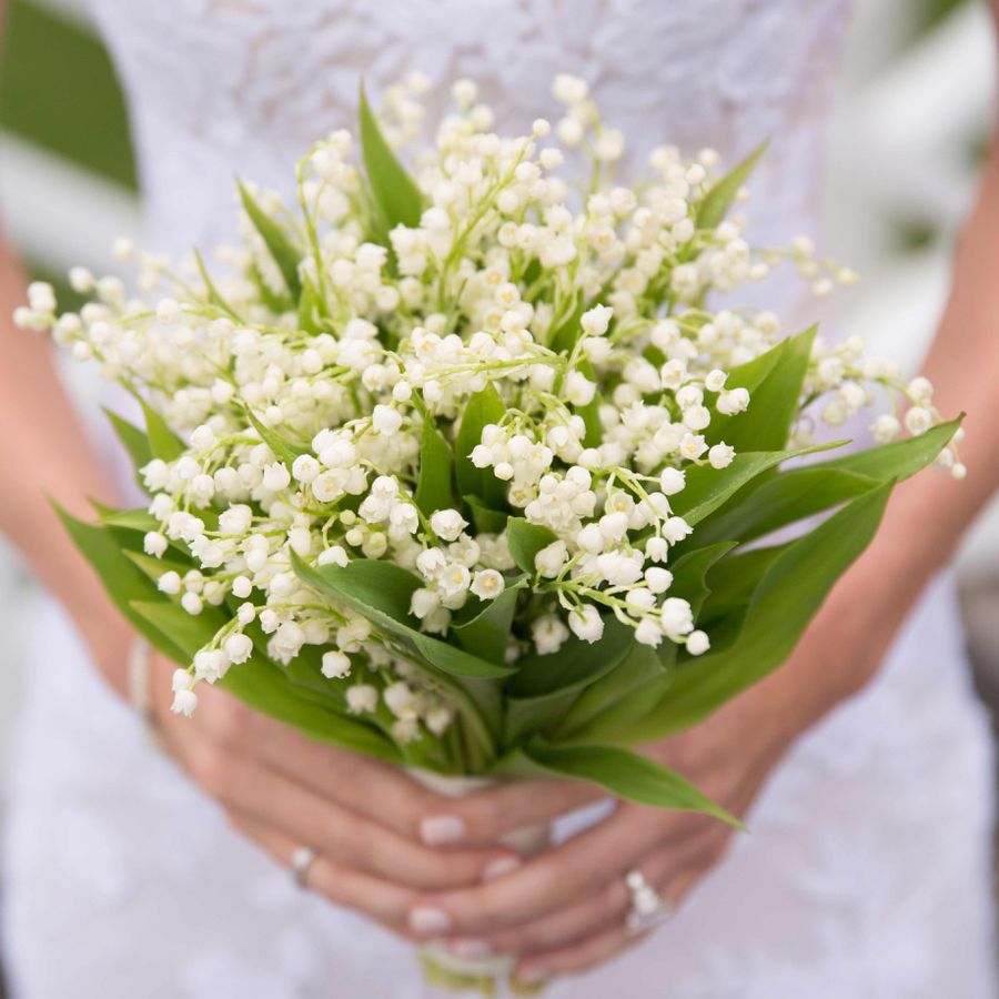 Bride carrying a lily of the valley bouquet at wedding