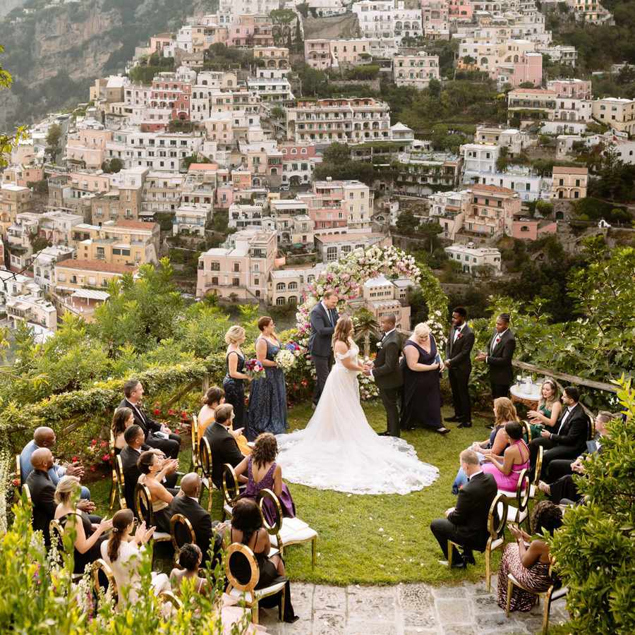 Bride and groom exchanging vows overlooking the Amalfi Coast with small number of guests sitting in front of them