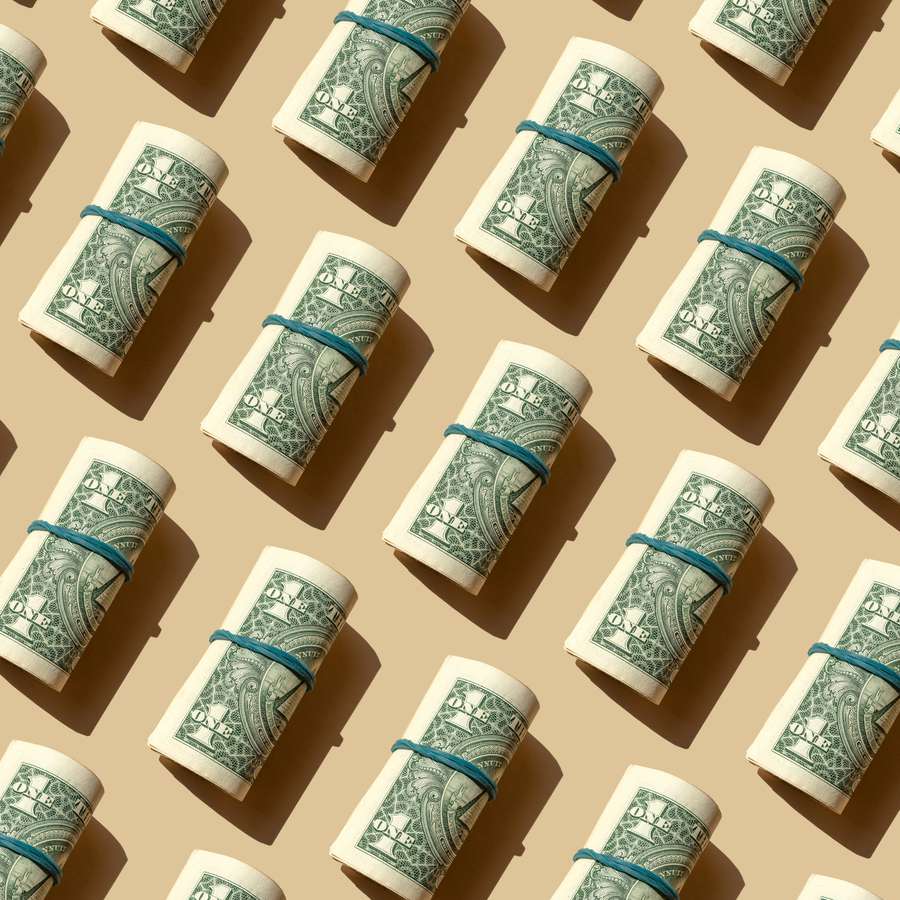 rolled money with blue rubber band on cream background