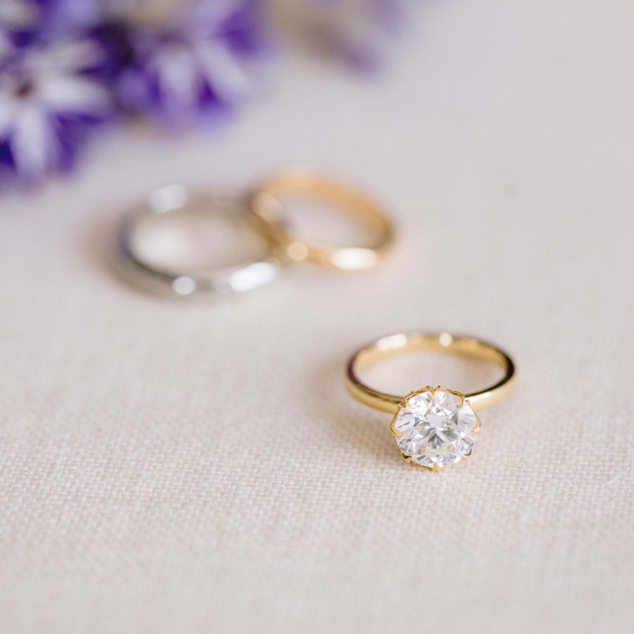 styled shot of an engagement ring and wedding bands