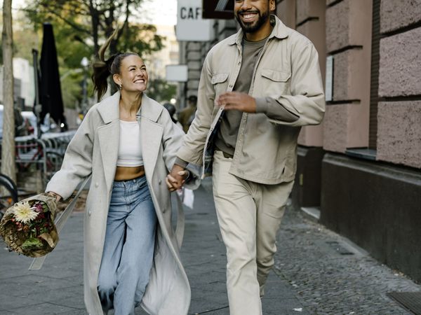 Couple holding hands and smiling while walking down the street