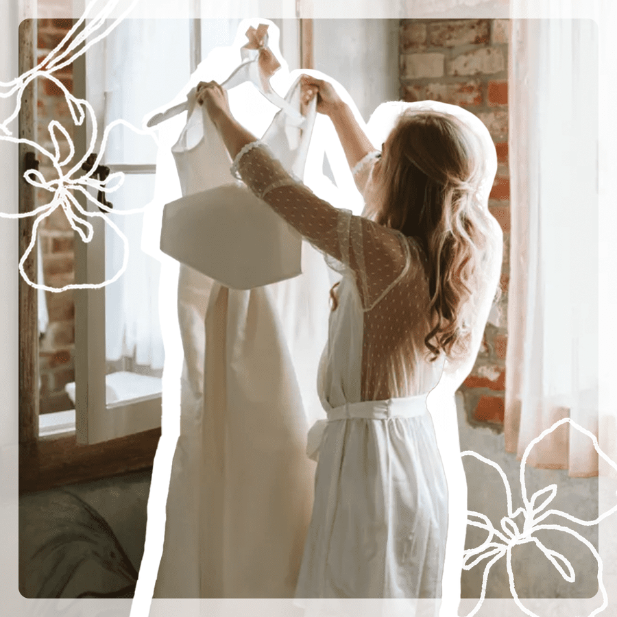 bride in getting-ready robe taking her wedding dress off the hanger